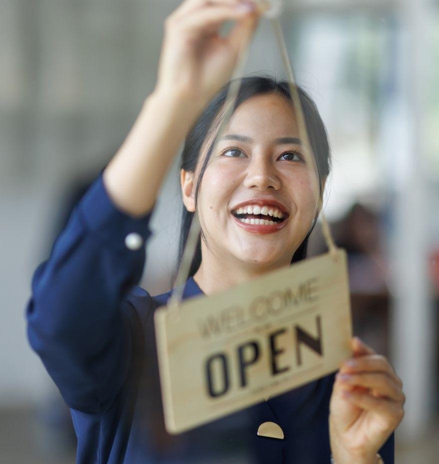 Happy business owner hanging open sign